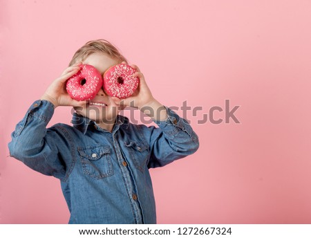 Child boy with pink donuts against pink background. Kid with donut. Funny time with food. Happy children while eat obese. Stylish little kid.