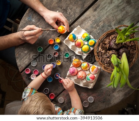 Easter day. Family preparing for Easter. Father and son painting Easter eggs on wooden background.