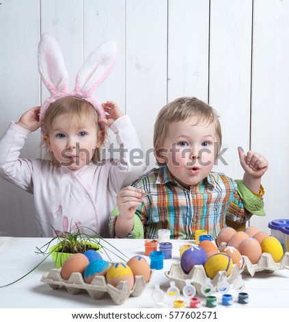 Easter day. Moden Family preparing for Easter. Son painting eggs on wooden background. Having fun on Easter egg hunt. Cute child boy and girl wearing bunny ears. colorful eggs in basket.
