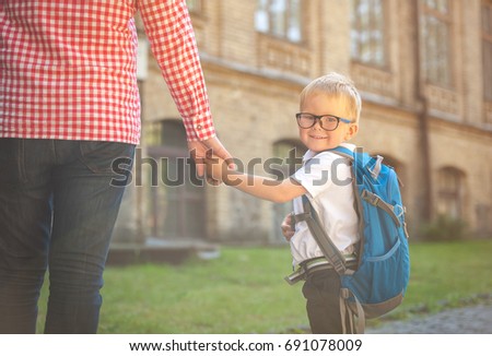 Parent taking child to school. Pupil of primary school go study with backpack outdoors. Father and son go hand in hand. Beginning of lessons. Back to school. First day of fall. Elementary student.