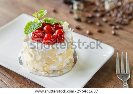 Mini vanilla cream cake with almond wrapped and topping with cherry.