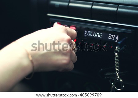 A female hand pushing the power button to turn on the car stereo system.