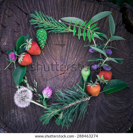 Young summer flower and fruit wreath on wooden background
