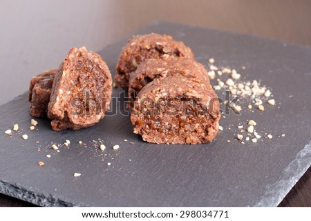 chocolate swiss roll with fruit jam on black background, close up, horizontal