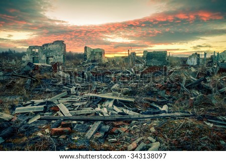 The remains of destroyed houses at sunset. Apocalyptic landscape