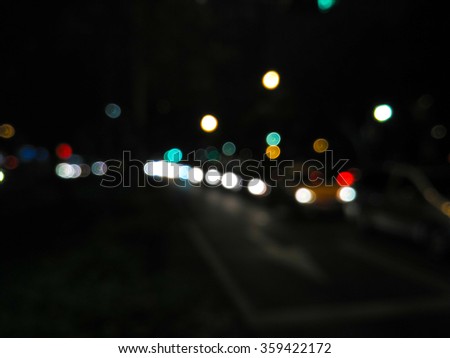 De focused/blur image of city at night. A man crossing the road. De focused, blurred urban abstract traffic background.