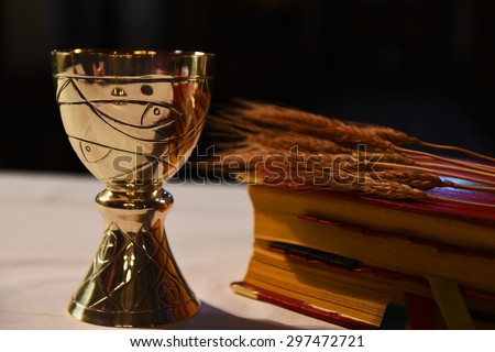 Golden chalice, prayer book and ear of wheat.