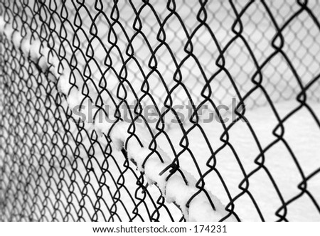 black and white image of a chain linked fence with snow.