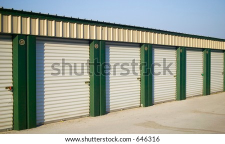 A line of rental storage units with roll-up corrugated metal doors.