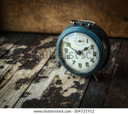 old blue retro alarm clock on dark wooden background