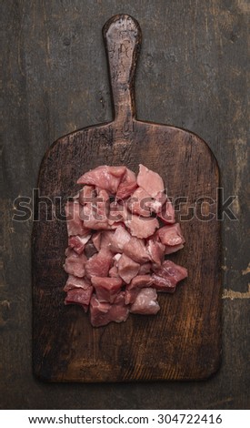 raw stew on the old board on a dark textured background, top view