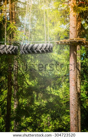 climbing forest or rope park with tire hanging on the ropes on nature background