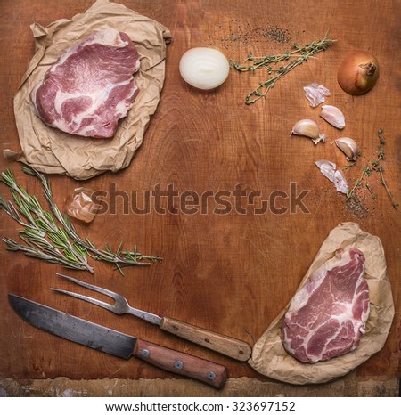 ingredients for cooking pork steaks with knife for meat and meat fork on  rustic wooden background top view,frame