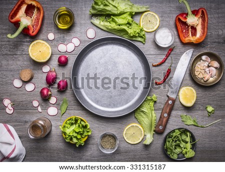 concept cooking vegetarian food ingredients laid out around the pan with a knife and spices space for text on rustic wooden background top view