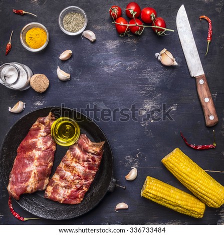 Ingredients for cooking double  raw lamb ribs in a cast iron frying pan with vegetables and spices on dark blue wooden rustic background top view place for text,frame