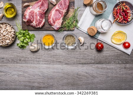 two steaks with oil and spices on cutting board  with lemon, salt and meat fork, sliced mushrooms, napkin border ,with text area on wooden rustic background top view