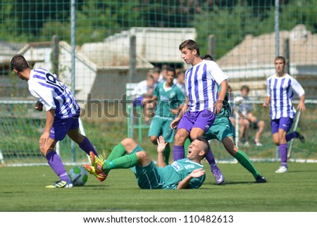 KAPOSVAR, HUNGARY - AUGUST 18: Unidentified soccer players in action at the Hungarian National Championship under 18 game between Kaposvar (green) and Ujpest (purple) August 18, 2012 in Kaposvar.