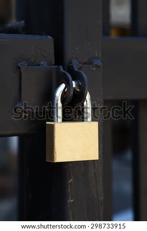 Closeup brass padlock on a black metal gate.
