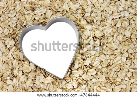 tilted white heart outlined with silver on a bed of oatmeal; white heart can be filled with text