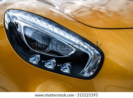 Closeup headlights of modern sport yellow car. Car exterior details