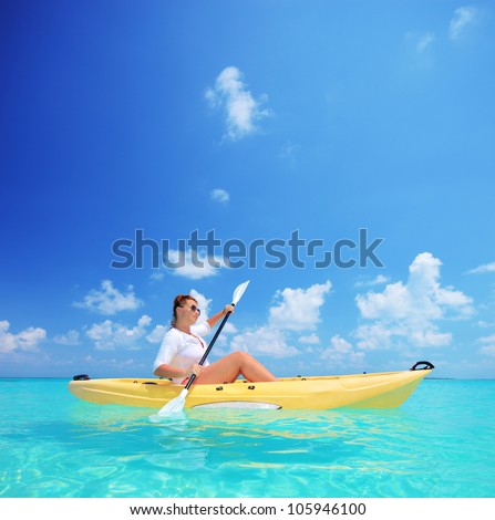 A young female in a yellow kayak kayaking near a Kuredu island, Maldives, Lhaviyani atoll