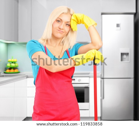 A tired female cleaner resting after cleaning a kitchen