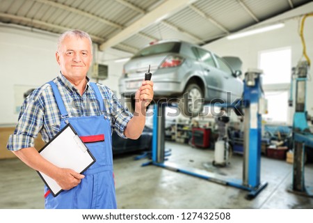 Auto mechanic holding a car key at auto repair shop during an automobile maintenance service