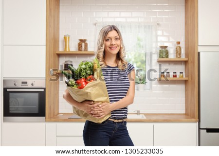 Young woman holding a grocery bag in a modern kitchen