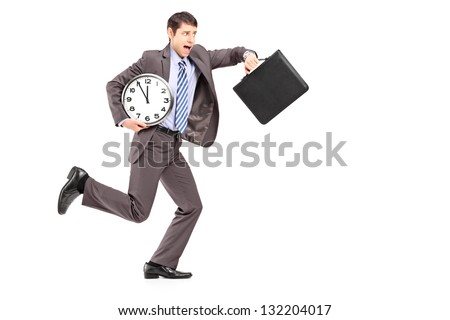 Full length portrait of a young businessman running late with a clock and a briefcase isolated on white background