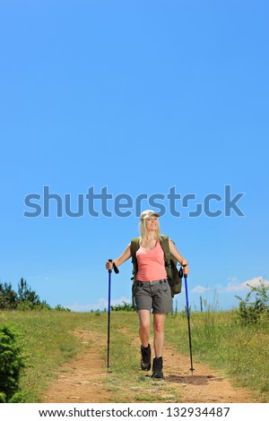Young female with backpack and hiking poles walking in the mountain