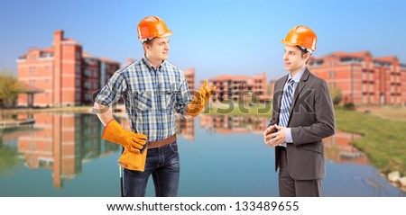 Male manual worker having a conversation with architect, buildings in the background