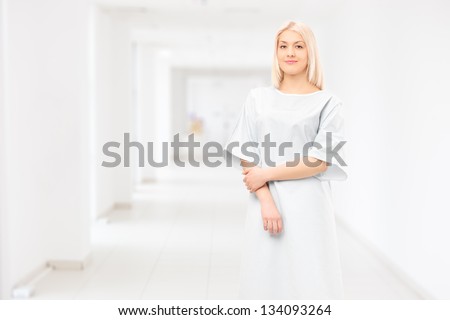 Female patient wearing hospital gown and posing in a hospital corridor