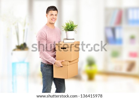 A young man carrying removal boxes in an apartment