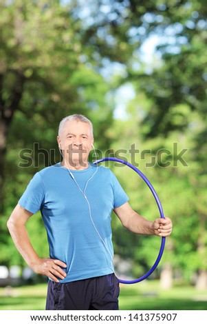 Fit mature man holding a hula hoop in a park