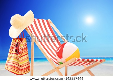 Beach chair with ball, bag and hat at sunny day by the sea