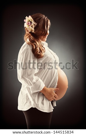 Pregnant woman in white shirt holding her belly