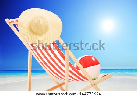 Beach chair with ball and hat on a sunny day by the sea