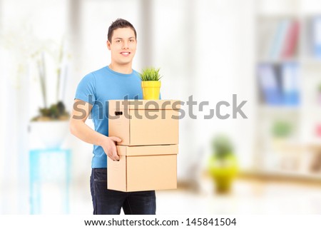 Smiling guy carrying removal boxes during moving into a new house