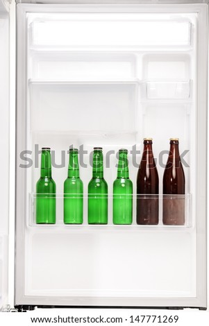 Close up of an open fridge full of beer bottless