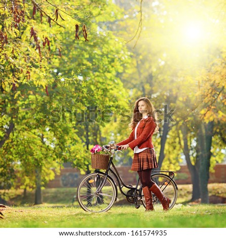 Young female with bicycle relaxing in a park on a sunny day, shot with a tilt and shift lens
