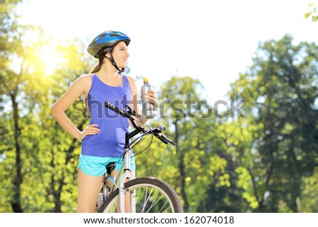 Young female biker posing on a mountain bike outdoor on a sunny day