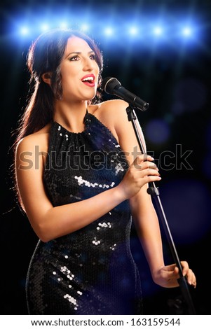 Glamorous young woman in black dress singing