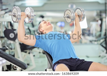 Young muscular man lifting weights in a gym