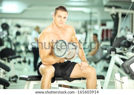 Shirtless muscular guy lifting weights in a gym