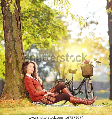 Young beautiful female with bicycle relaxing in a park on a sunny day, shot with a tilt and shift lens