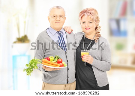 Mature couple standing close together holding a healthy food and drink at home