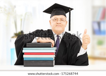 Middle aged college professor seated on table with stack of books and giving thumb up isolated on white background