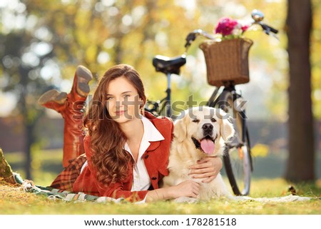 Pretty female lying down with dog in a park
