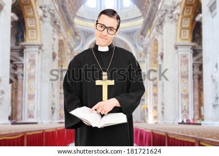 Young male priest pointing on a paragraph of the bible in a cathedral