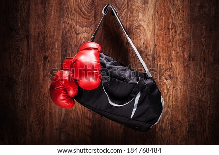 Sports bag and boxing gloves hanging on a wooden wall